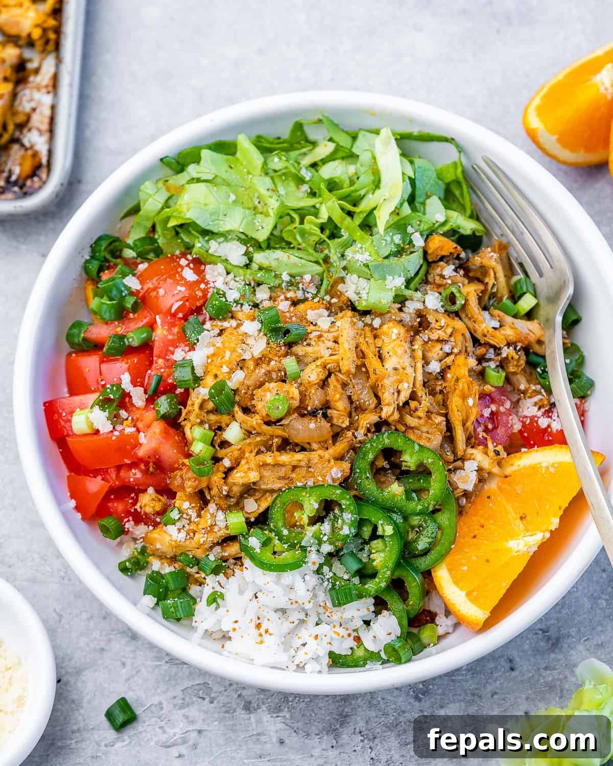Crispy Pulled Chicken Carnitas 2 A vibrant bowl of chicken carnitas with fresh greens, rice, and tomatoes, ready to eat.