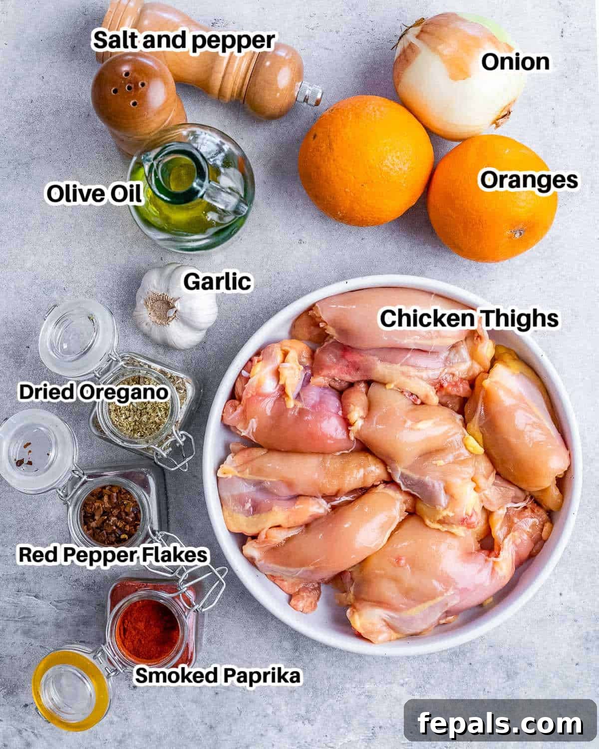 Crispy Pulled Chicken Carnitas 3 A flat lay showing all the fresh ingredients needed to make chicken carnitas: boneless chicken thighs, oranges, onion, garlic, and a selection of spices including red pepper flakes and smoked paprika.
