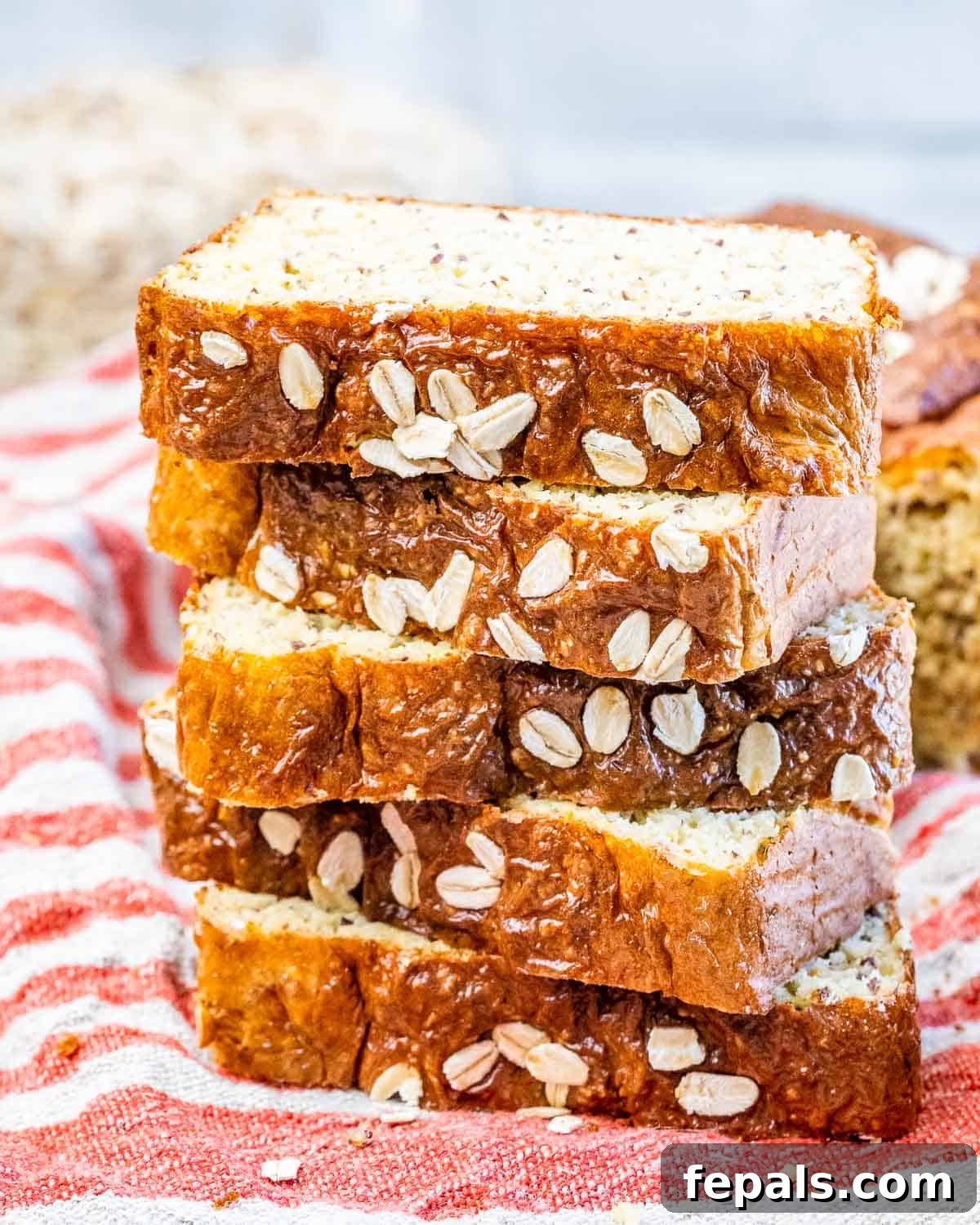 Golden Cottage Loaf 2 Five golden-brown slices of high-protein cottage cheese bread, made with oats, stacked on a colorful striped towel, showcasing its inviting texture.