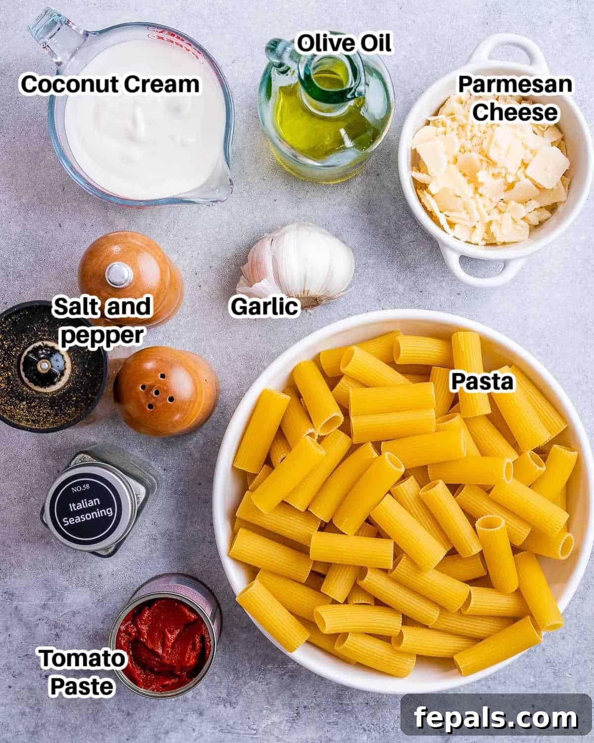 Essential ingredients for Gigi Hadid Pasta laid out on a rustic surface, including pasta, garlic, tomato paste, coconut cream, and fresh herbs.