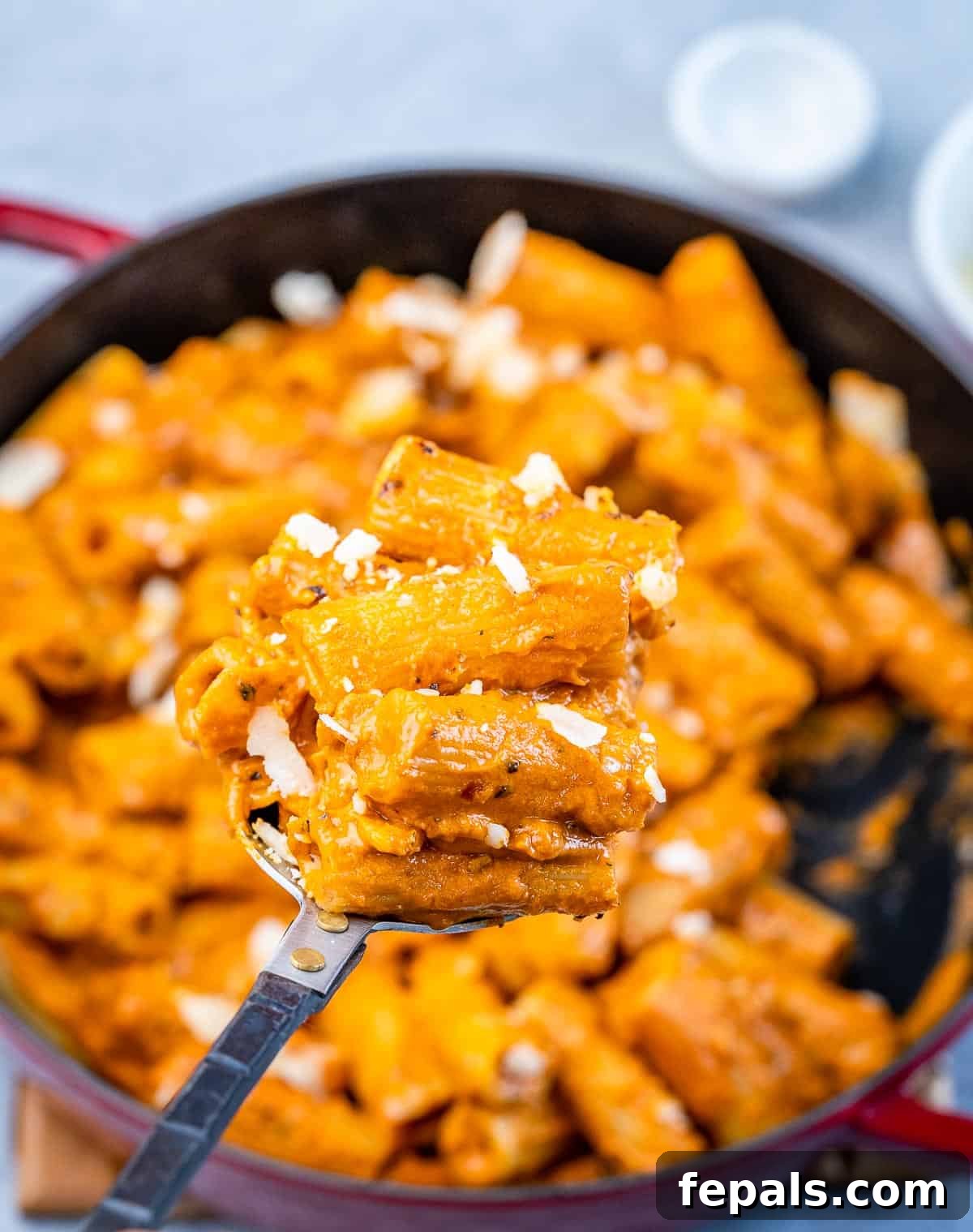 A serving of Gigi Hadid Pasta scooped directly from a red skillet onto a plate, garnished with fresh herbs.
