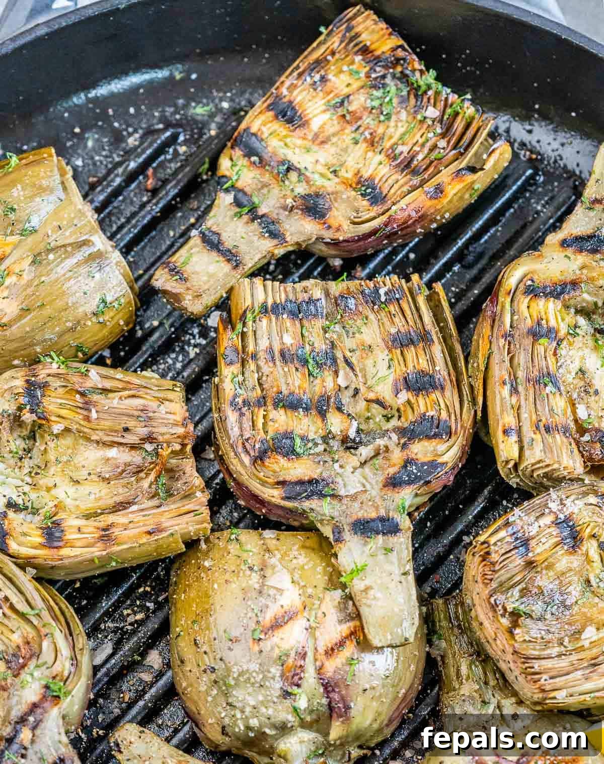 Smoky Grilled Artichoke Halves 8 Delicious grilled artichoke halves showcasing beautiful char marks, sizzling on a hot grill pan, ready to be served.