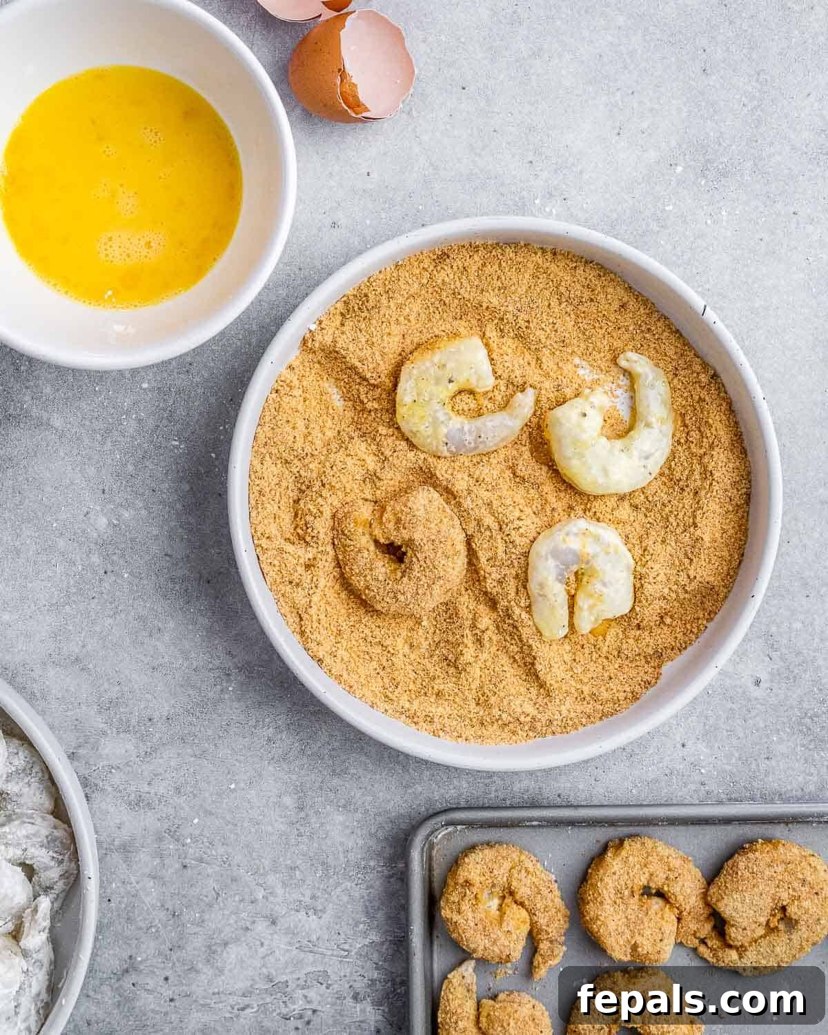 Shrimp being coated in breadcrumbs, preparing for cooking to achieve a crispy texture.