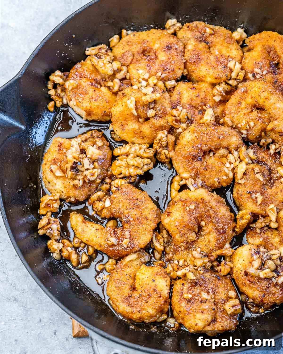 A vibrant close-up of Honey Walnut Shrimp artfully arranged in a skillet, ready to be served.