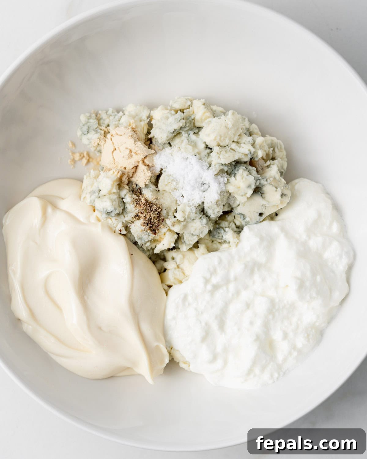 Decadent Blue Cheese Dip 4 Blue cheese, mayo, sour cream and seasonings in a white bowl.