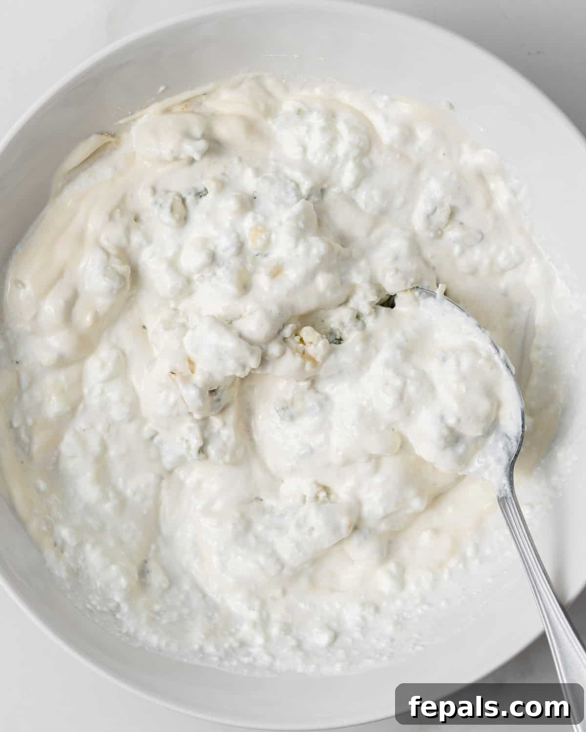 Decadent Blue Cheese Dip 5 Stirring blue cheese crumbles into sour cream and mayo.