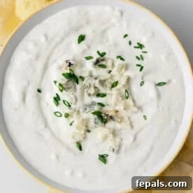 Decadent Blue Cheese Dip 8 a round bowl of blue cheese dip topped with more crumbled blue cheese and sliced chives.