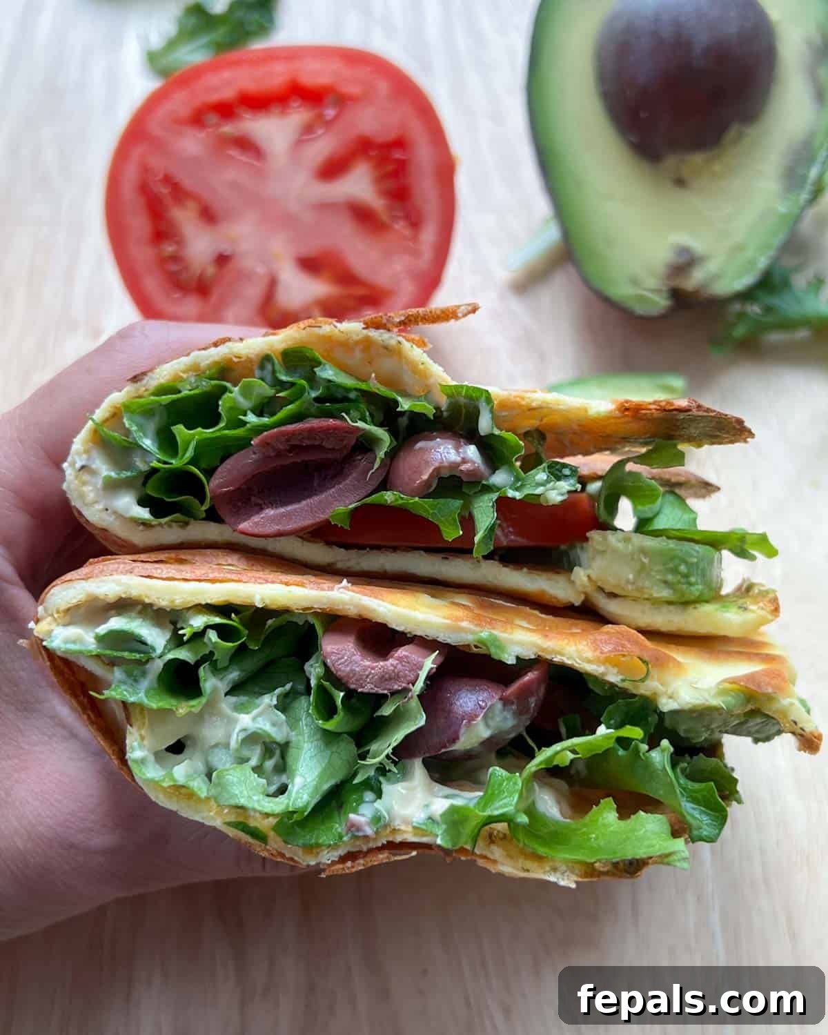 The Viral Cottage Cheese Wrap 2 hand holding two halves of cottage cheese wrap, filled with fresh vegetables and yogurt.