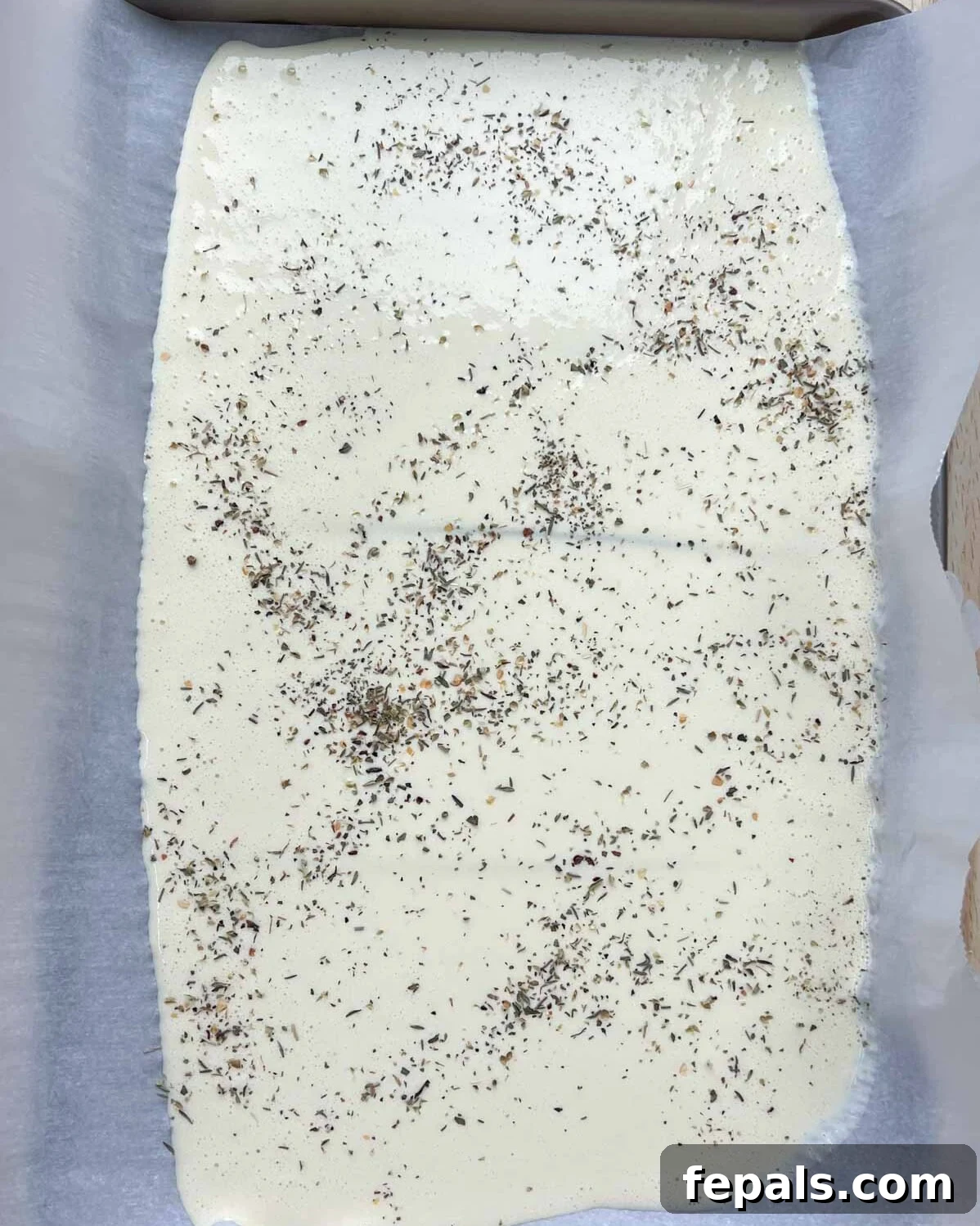 The Viral Cottage Cheese Wrap 6 Italian seasoning is added over the cottage cheese batter poured onto a sheet pan.