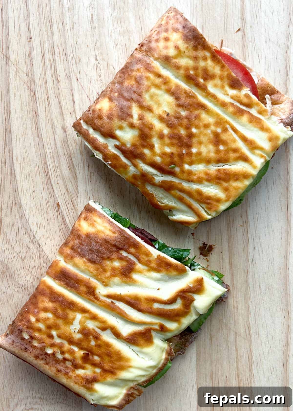 The Viral Cottage Cheese Wrap 10 cottage cheese wrap sandwich cut in half on a cutting board, filled with fresh ingredients.