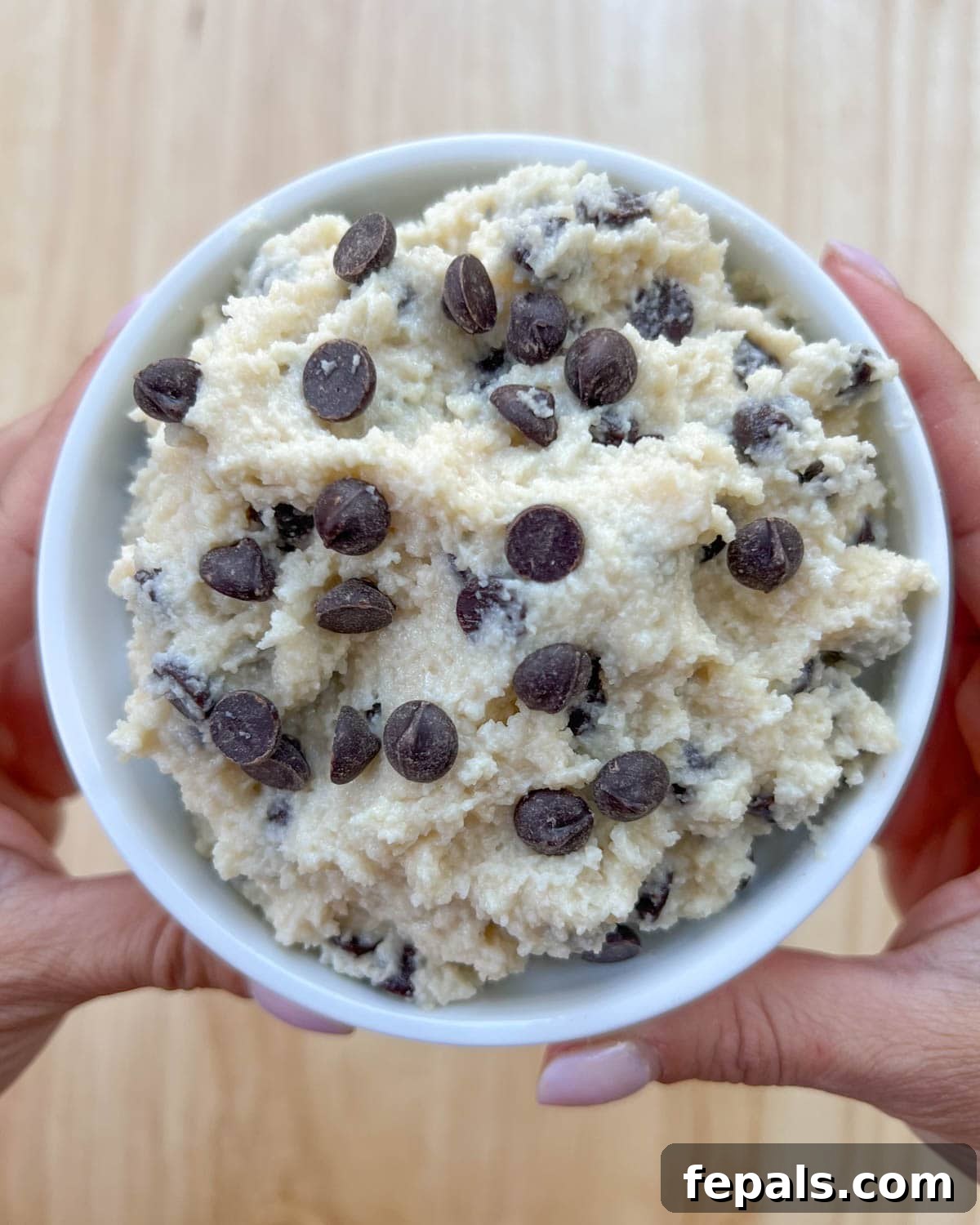 Protein-Packed Cookie Dough Delight 12 A hand holding a bowl of the edible cottage cheese cookie dough, showcasing its rich texture and chocolate chips.