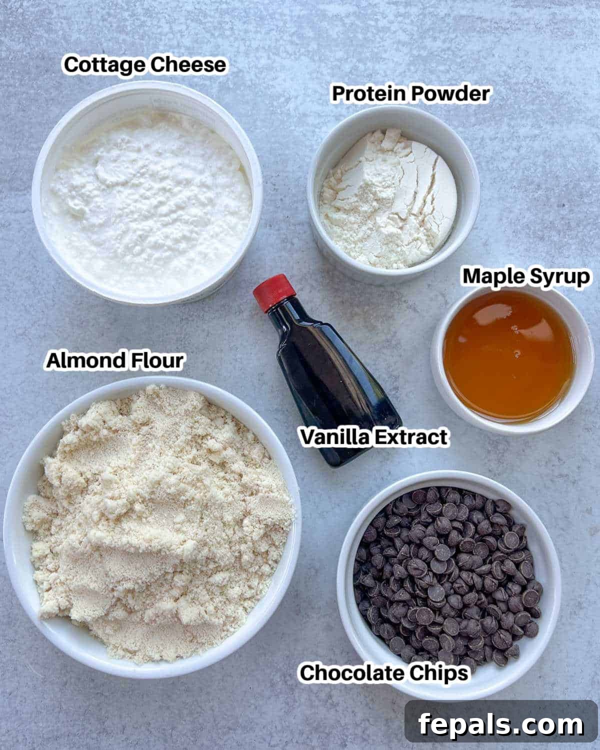 Protein-Packed Cookie Dough Delight 3 A selection of ingredients laid out, including cottage cheese, almond flour, maple syrup, vanilla extract, protein powder, and chocolate chips, ready for making edible cookie dough.