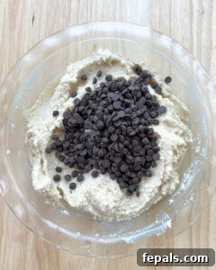 chocolate chips are added over cookie dough in a dish.