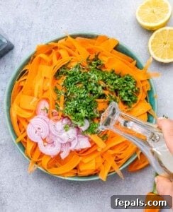 Adding shallots, cilantro and dressing over carrot salad.