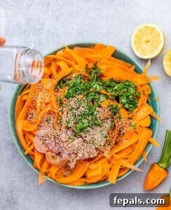 Sprinkling sesame seeds over a salad with shredded carrots, cilantro and shallots.