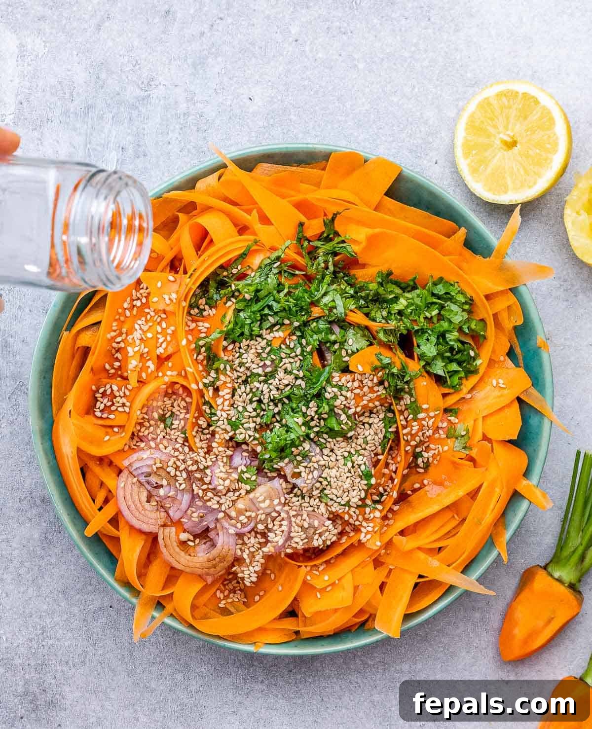 Viral Carrot Salad Sensation 7 Toasted sesame seeds being sprinkled over the mixed carrot salad with cilantro and shallots.