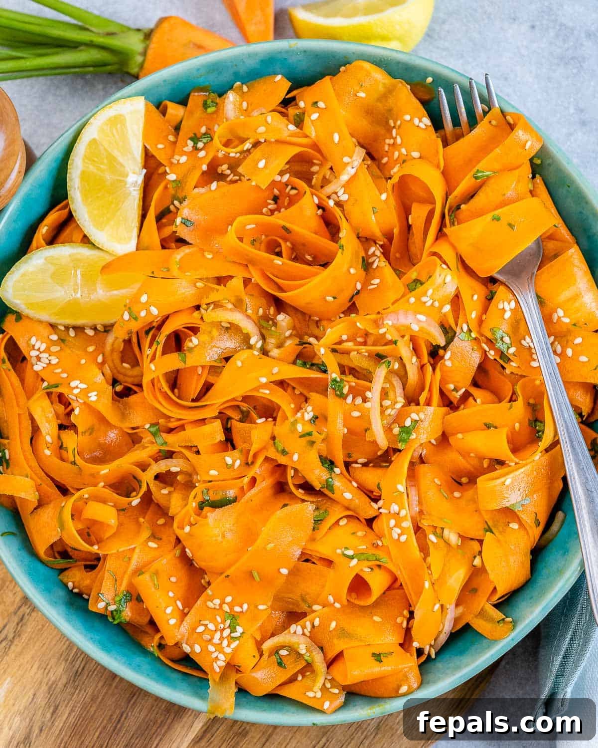 Viral Carrot Salad Sensation 8 A round blue plate presenting a serving of sliced carrot salad garnished with fresh cilantro and a lemon wedge on the side.