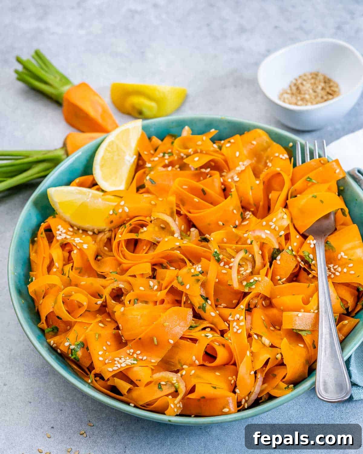 Viral Carrot Salad Sensation 9 A close-up shot of shredded carrot salad served in a elegant blue bowl, garnished with a vibrant lemon wedge, highlighting its fresh appeal.