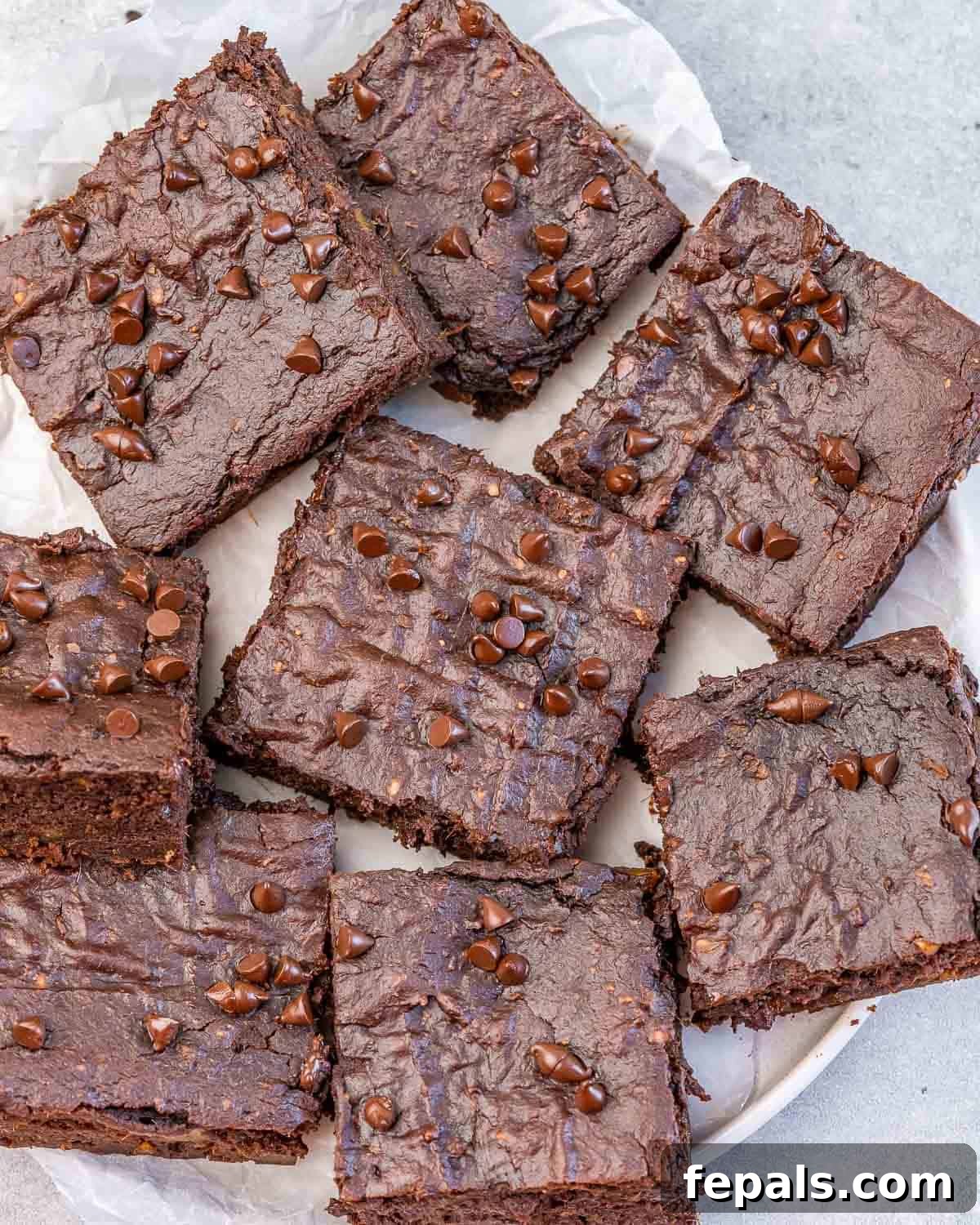 Close-up of perfectly cut sweet potato brownie squares arranged on a white plate, highlighting their rich, dark color and fudgy texture.