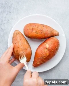 fork poking holes in sweet potatoes on a plate.
