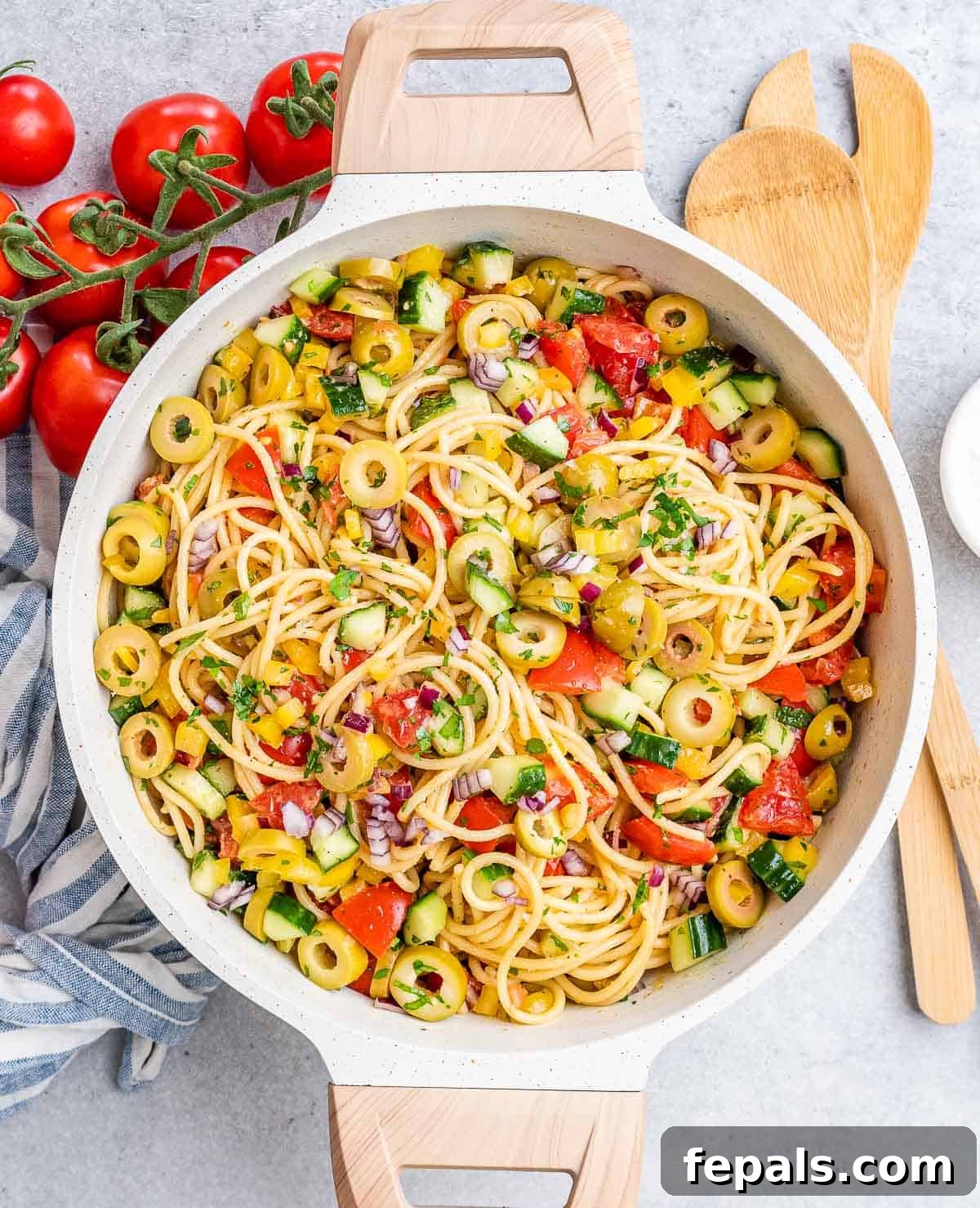 Refreshing Spaghetti Salad 2 A beautifully presented round white dish featuring a vibrant cold spaghetti salad, generously mixed with fresh vegetables and a savory dressing, ready to be enjoyed.
