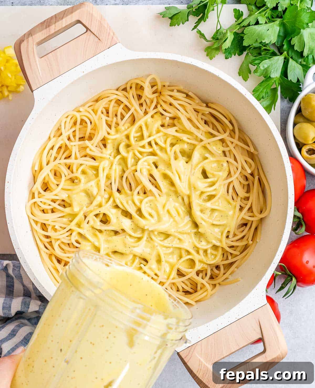 Refreshing Spaghetti Salad 6 A vibrant close-up shot of a creamy, pale yellow dressing being poured over a bed of cooked spaghetti in a large mixing bowl, ensuring full coverage.