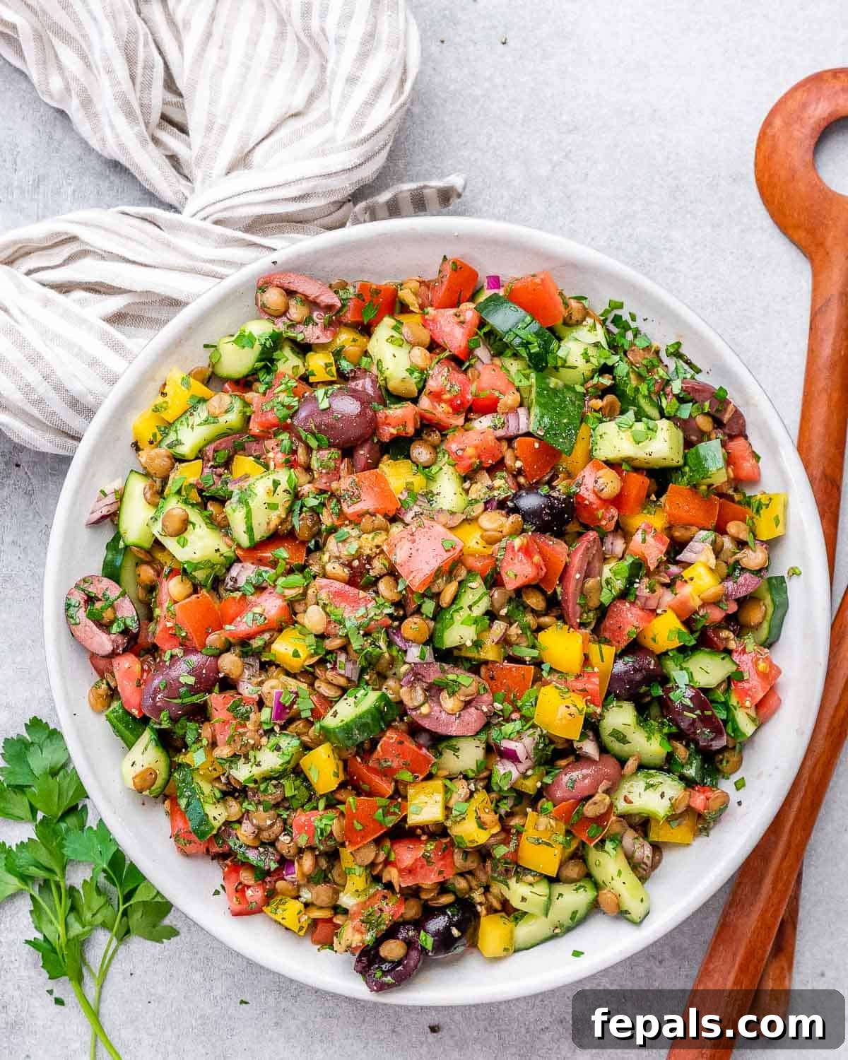 A vibrant, mixed lentil and veggie salad in a rustic round bowl, garnished with fresh herbs.