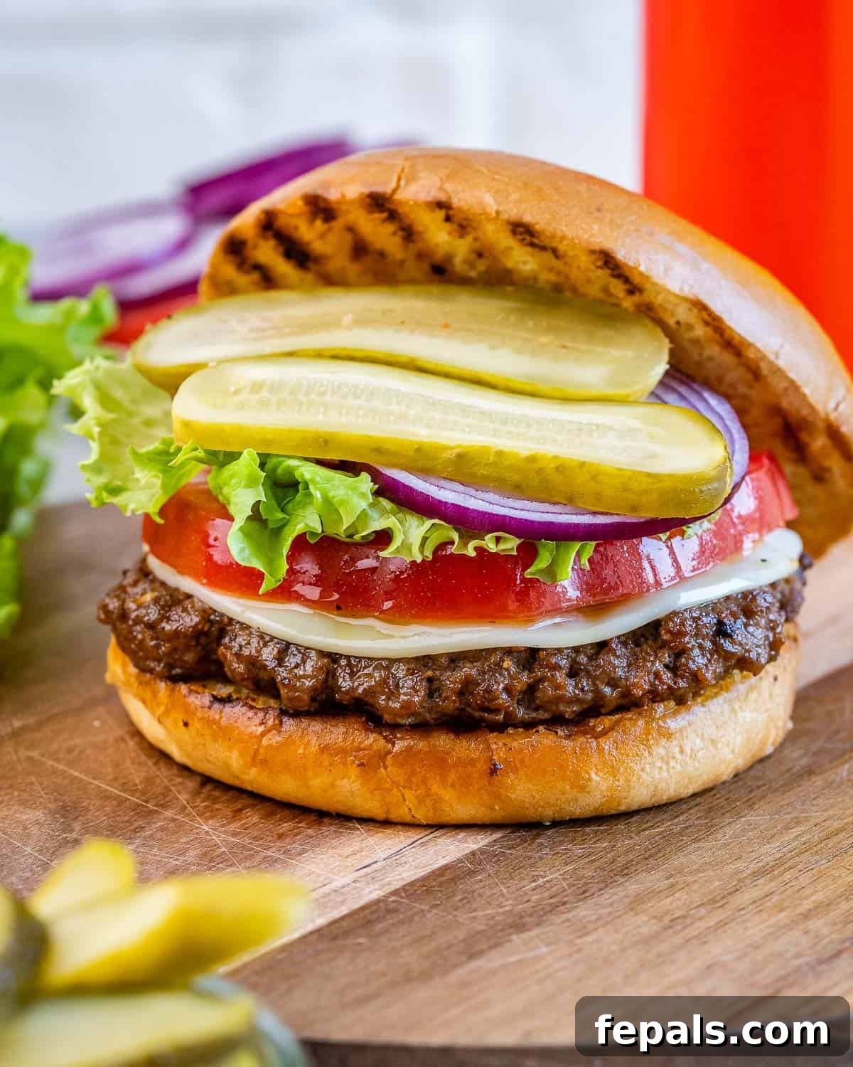 Burger Perfection, Made Easy 9 hamburger with top bun slightly off showing the patty, lettuce, tomatoes, and pickles.