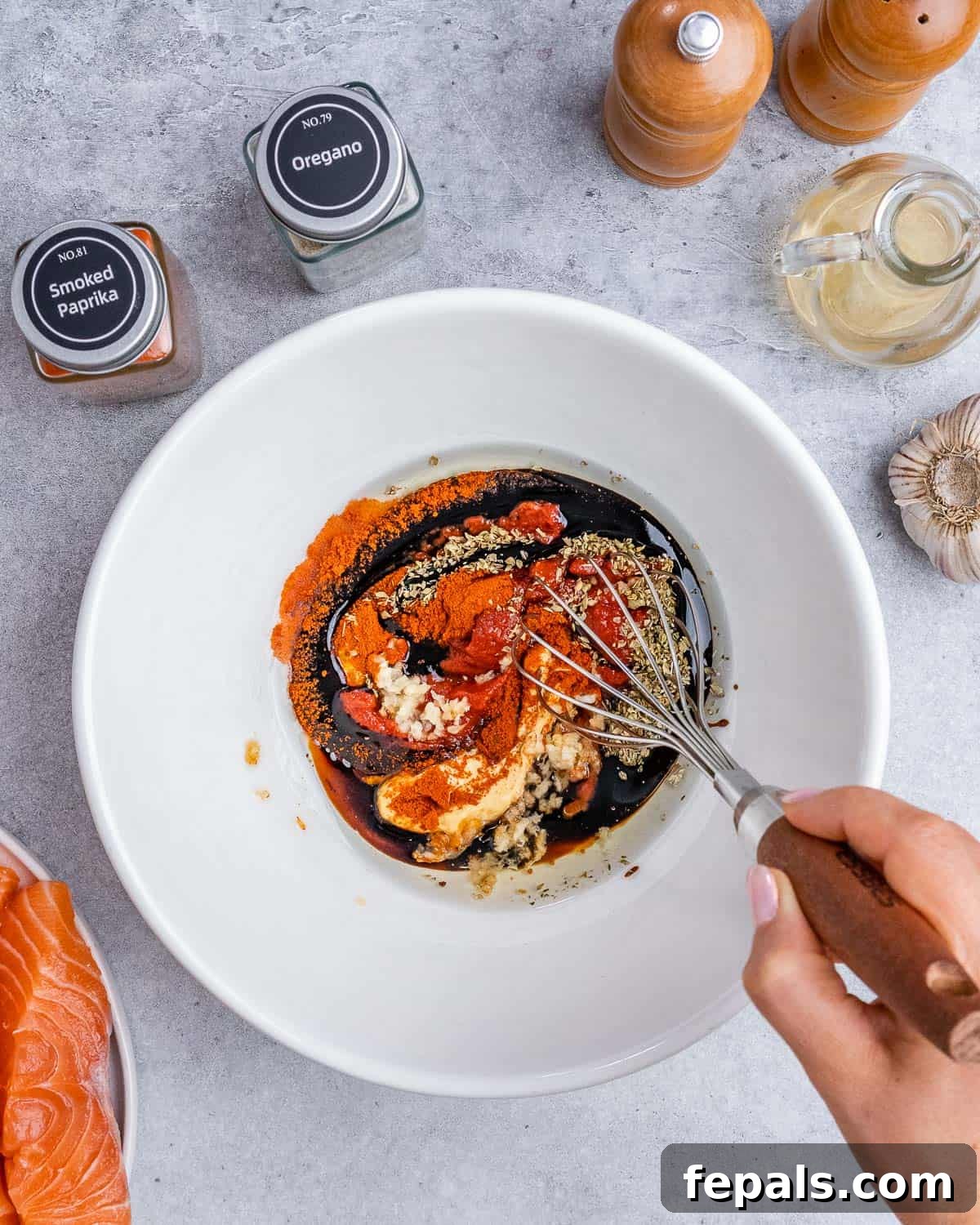 Whisking spices with avocado oil and balsamic glaze in a white bowl.