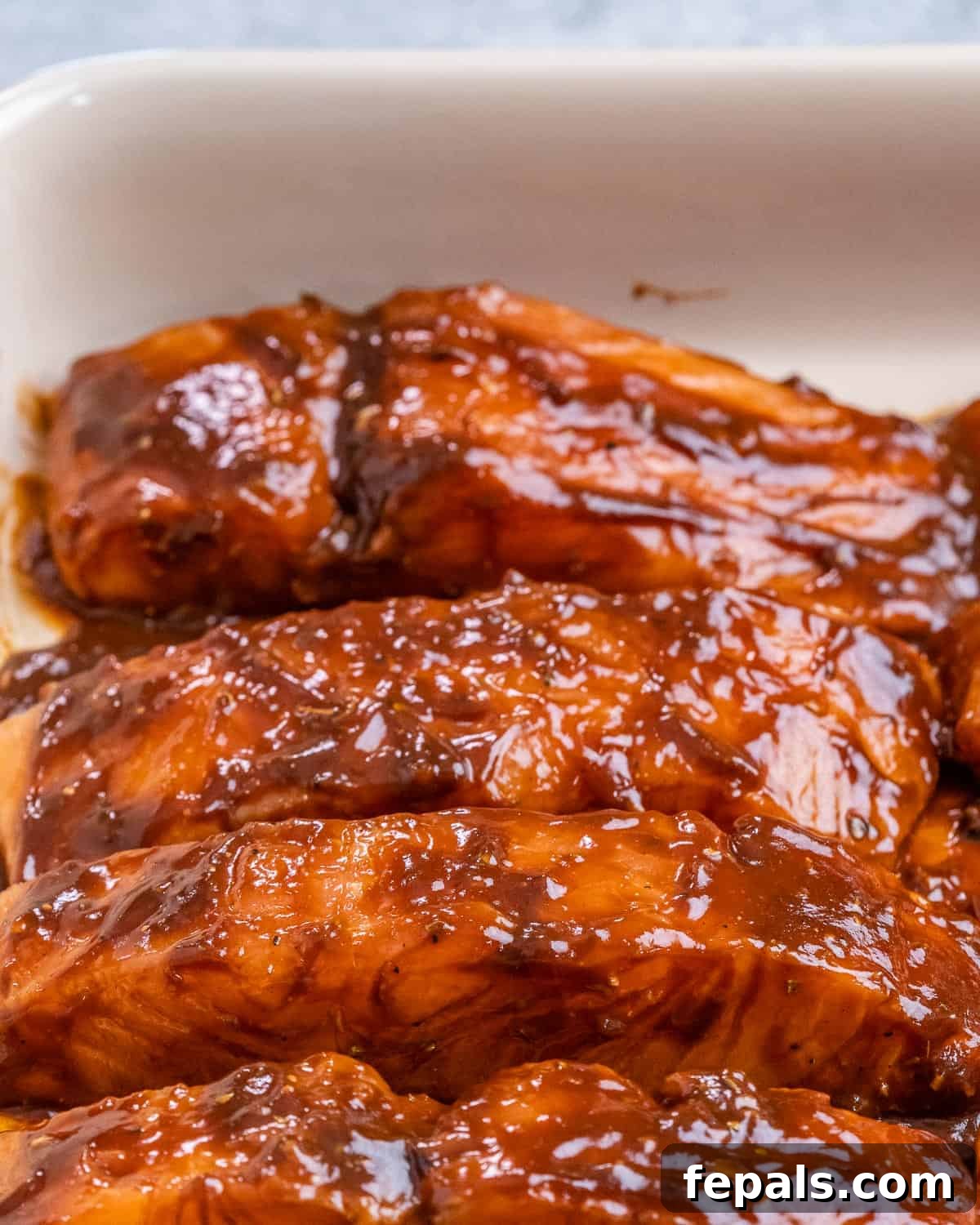 Adding salmon filets to a baking dish.