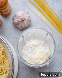 Cottage cheese, milk, and parmesan added to a blender, ready to be blended into a smooth sauce.