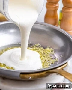 Sauce streaming into the hot skillet, mixing with the garlic and olive oil to begin thickening.