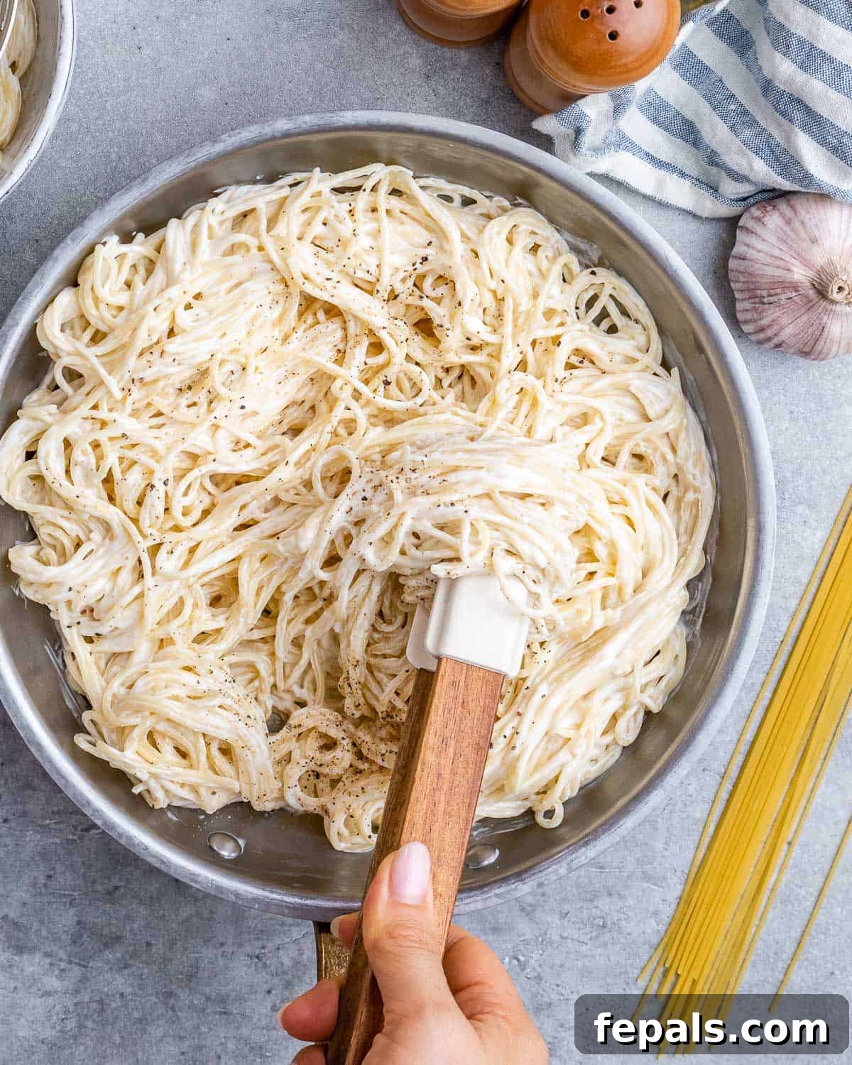 Velvety Cottage Cheese Alfredo 8 Hand stirring cooked spaghetti in a pan to evenly combine with the Alfredo sauce.