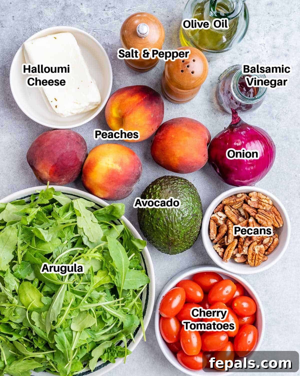 Ingredients to make grilled peach salad, including peaches, halloumi, greens, tomatoes, avocado, onion, and pecans.
