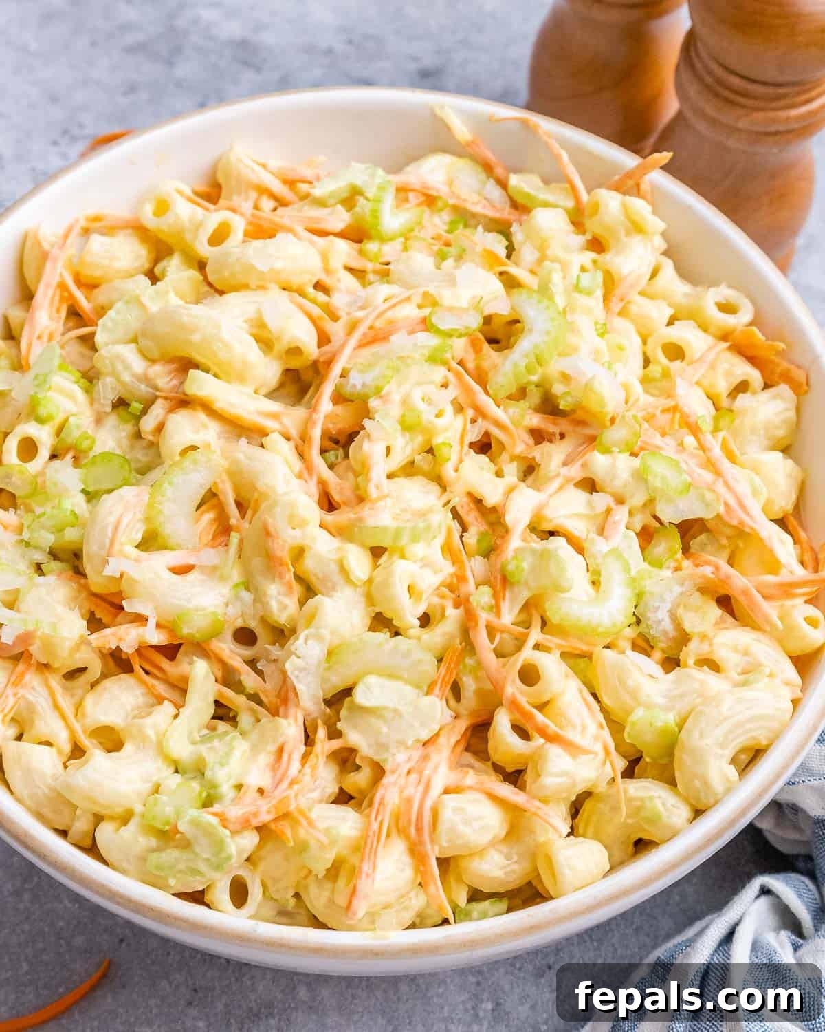 Aloha Macaroni Salad 2 A beautifully presented Hawaiian mac salad in a white bowl, garnished with shredded carrots and freshly ground black pepper, ready to be served and savored.
