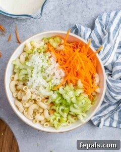 Aloha Macaroni Salad 13 Elbow macaroni topped with grated carrot, chopped celery, and grated onion, ready for mixing.