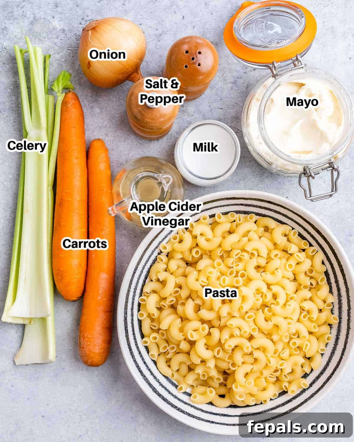 Aloha Macaroni Salad 4 A vibrant flat lay image showcasing all the fresh ingredients needed to make Hawaiian mac salad, including dry elbow macaroni, fresh carrots, celery, onion, a jar of mayonnaise, and a bottle of apple cider vinegar, ready for preparation.
