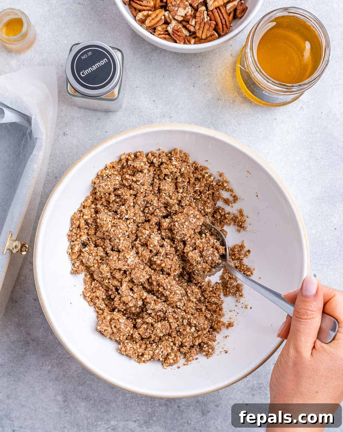 Stirring together almond flour with coconut sugar and honey in a white bowl.