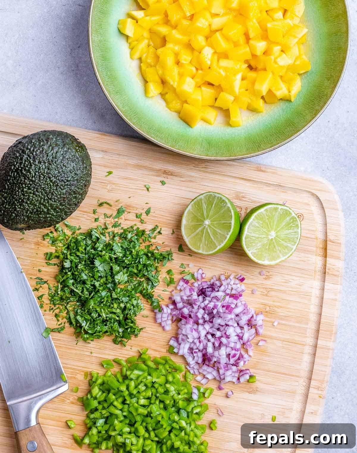 A mix of chopped onions, cilantro, and other vegetables, prepped for adding to the mango salsa.