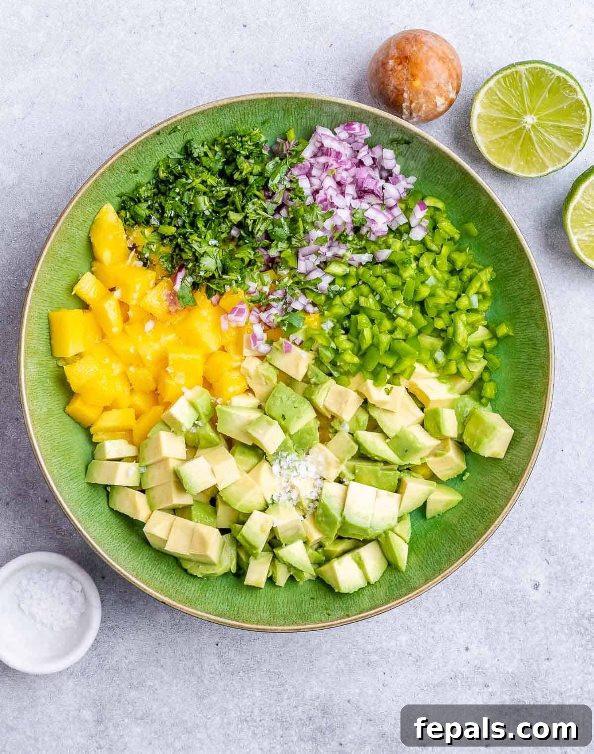 Chopped mango and vegetables combined in a bowl, awaiting dressing for the salsa.