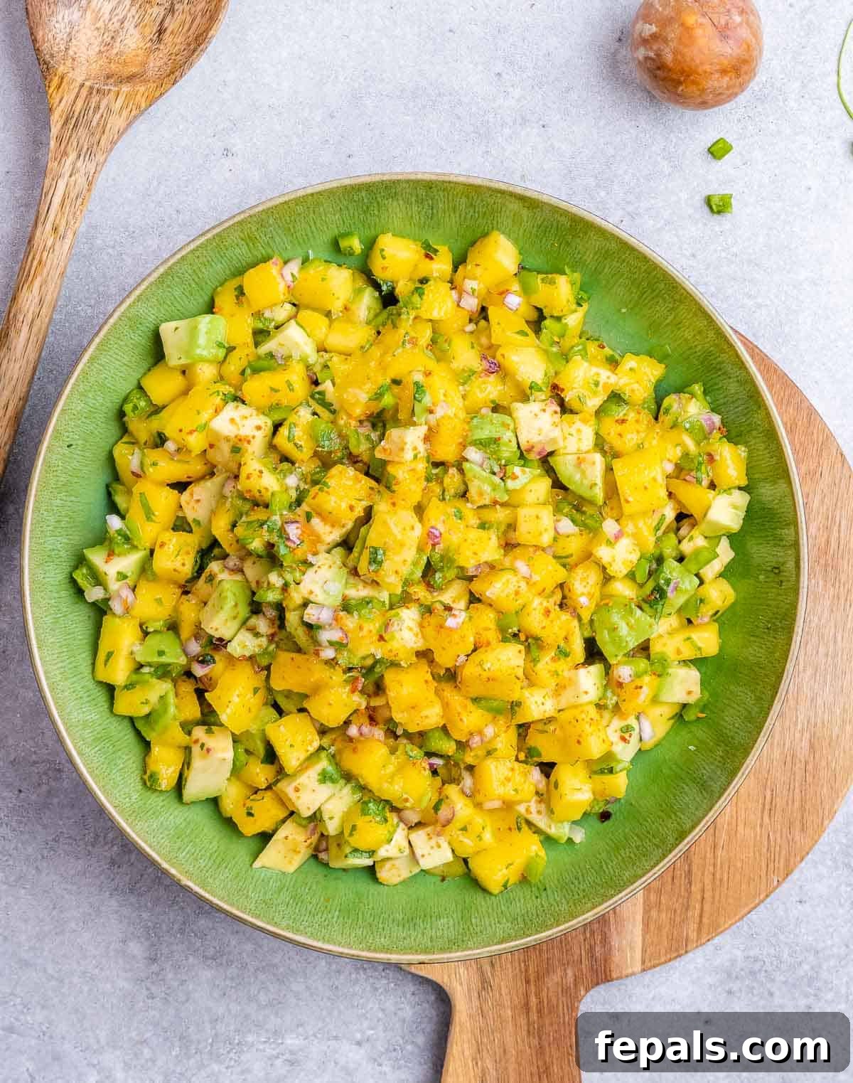 The fully mixed mango and vegetable salsa, presented in a green bowl, ready for serving.