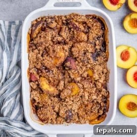 Wholesome Peach Cobbler 10 A white baking dish with baked peach cobbler and fresh sliced peaches on the right side of the dish.