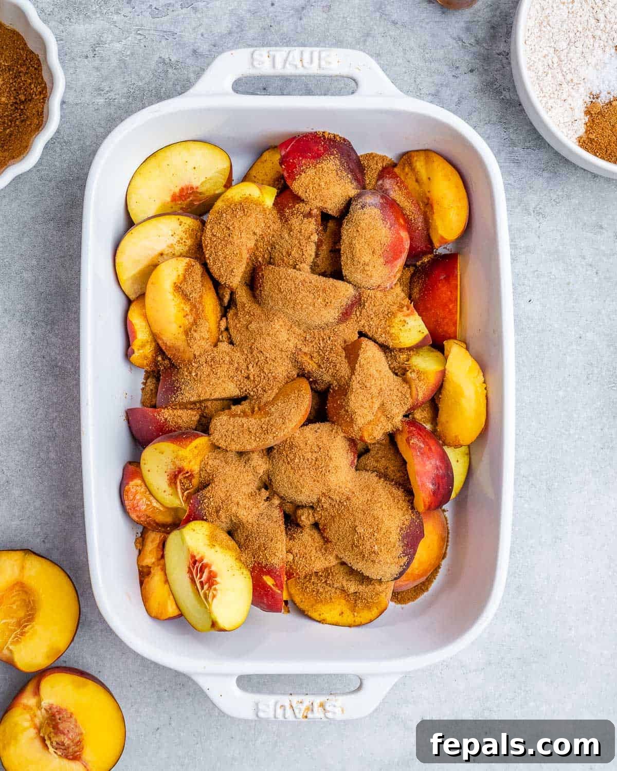 Wholesome Peach Cobbler 4 Adding sliced peaches and coconut sugar to a white casserole dish.