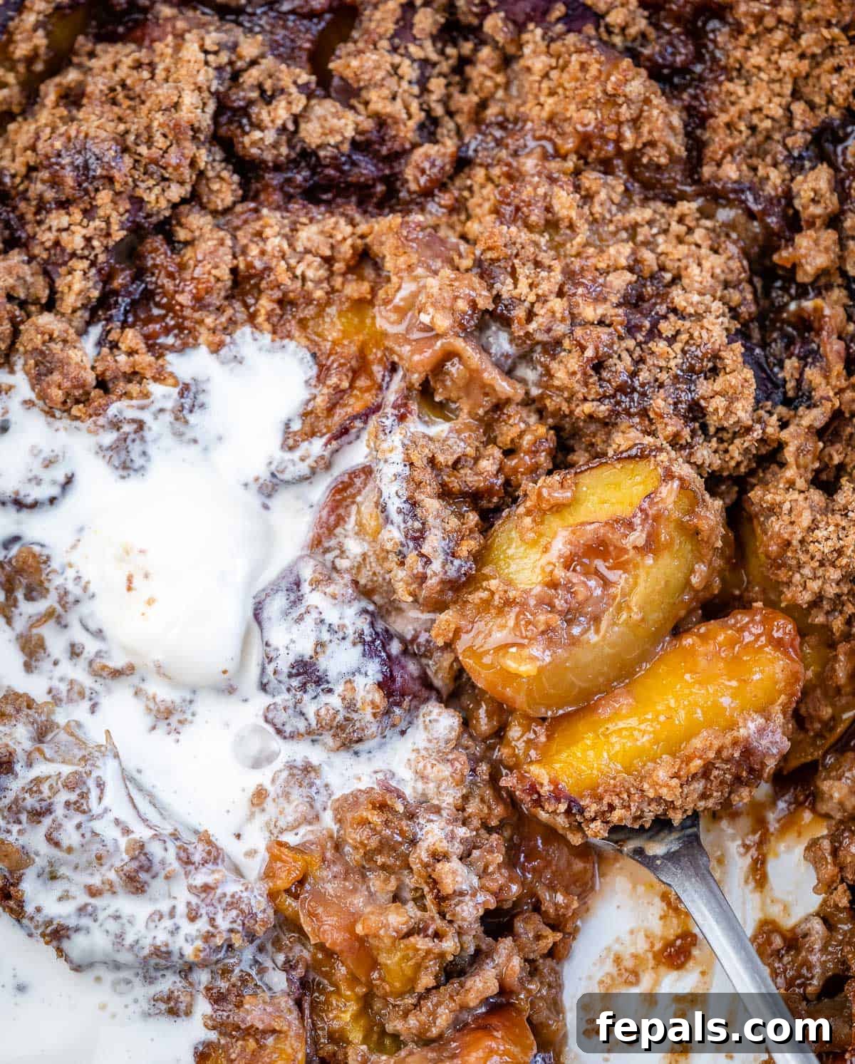 Wholesome Peach Cobbler 8 a spoon grabbing a serving of peach cobbler from the dish.