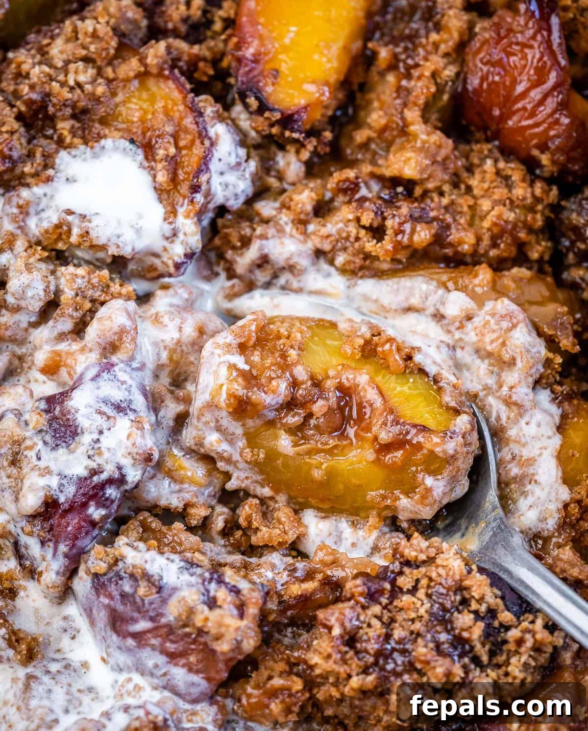 Wholesome Peach Cobbler 9 Serving spoon dishing into a peach cobbler with melted vanilla ice cream.