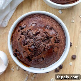 Chocolate baked oats in a round white ramekin, topped with a few chocolate chips.