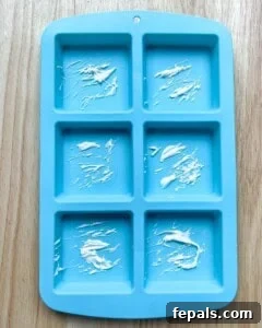 Drizzling melted white chocolate into a silicone mold for design.