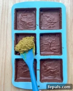 Adding the prepared pistachio and kataifi filling into the chocolate-lined molds.