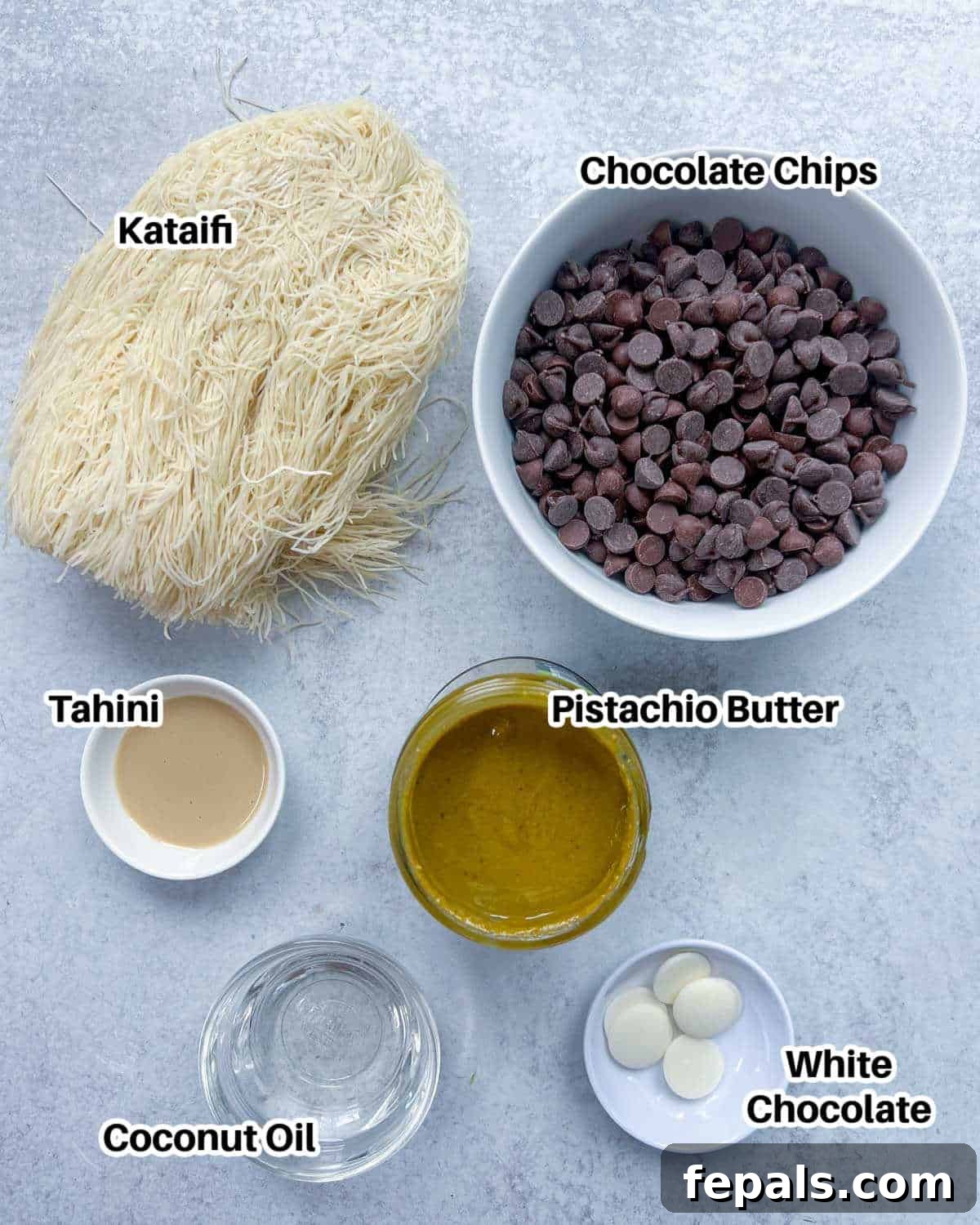 A flat lay photograph showcasing all the ingredients required to make the Dubai chocolate bar: chocolate chips, coconut oil, tahini, pistachio butter, and kataifi pastry.