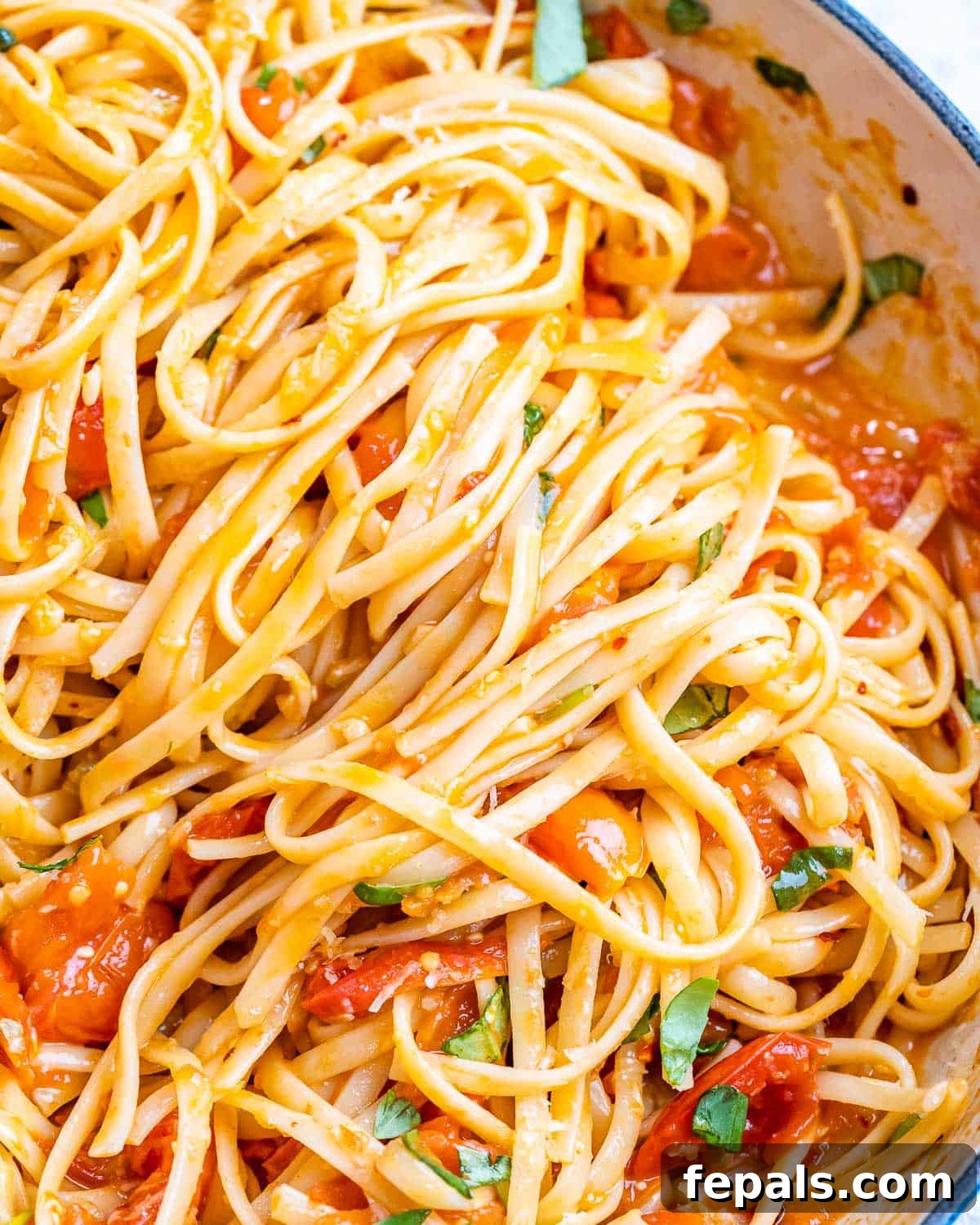 Fresh and Fast Tomato Basil Pasta 7 Pasta being tossed into the skillet with tomato basil sauce using kitchen tongs.